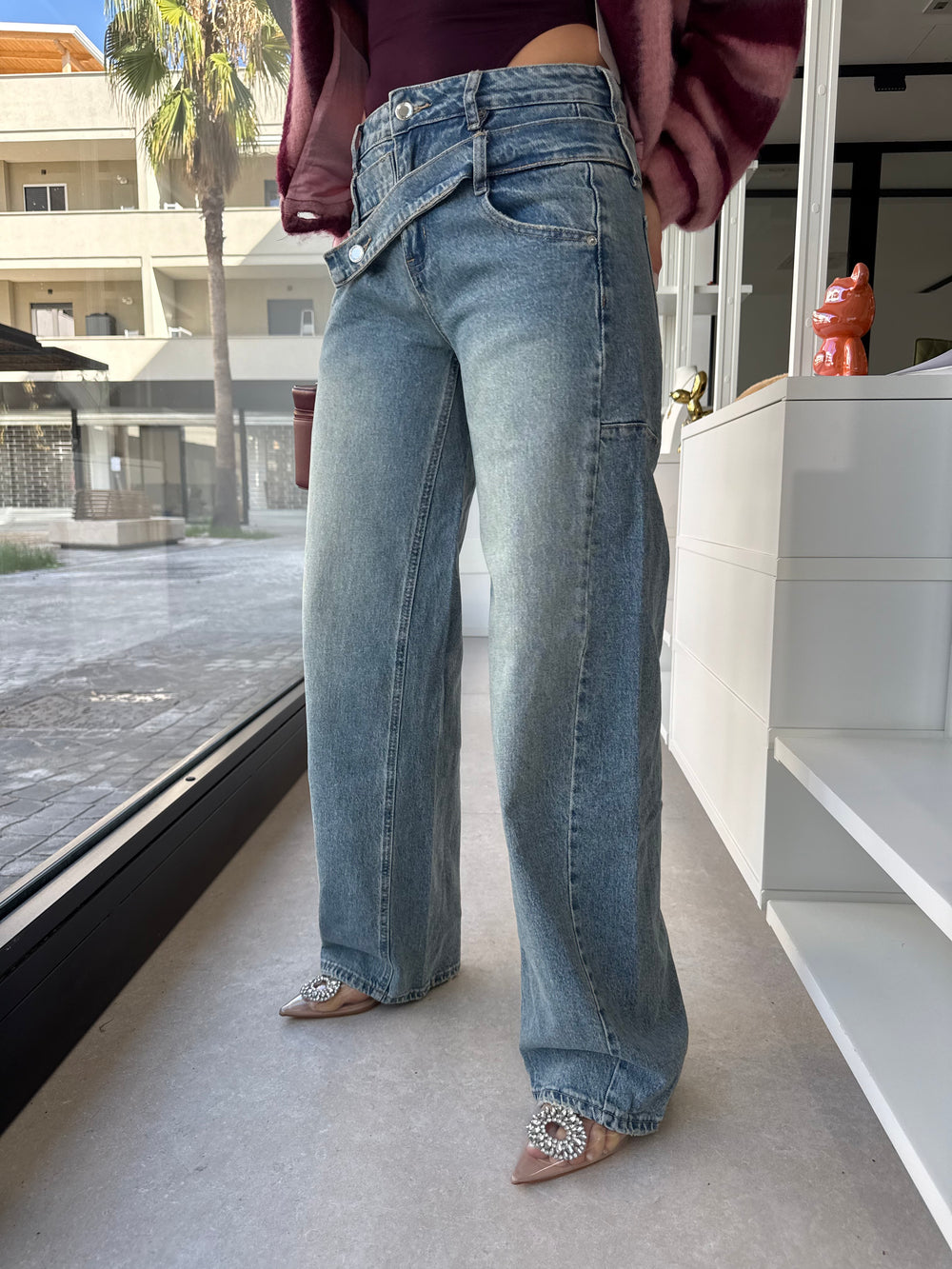 Jeans con bottone asimmetrico