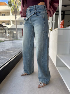 Jeans con bottone asimmetrico